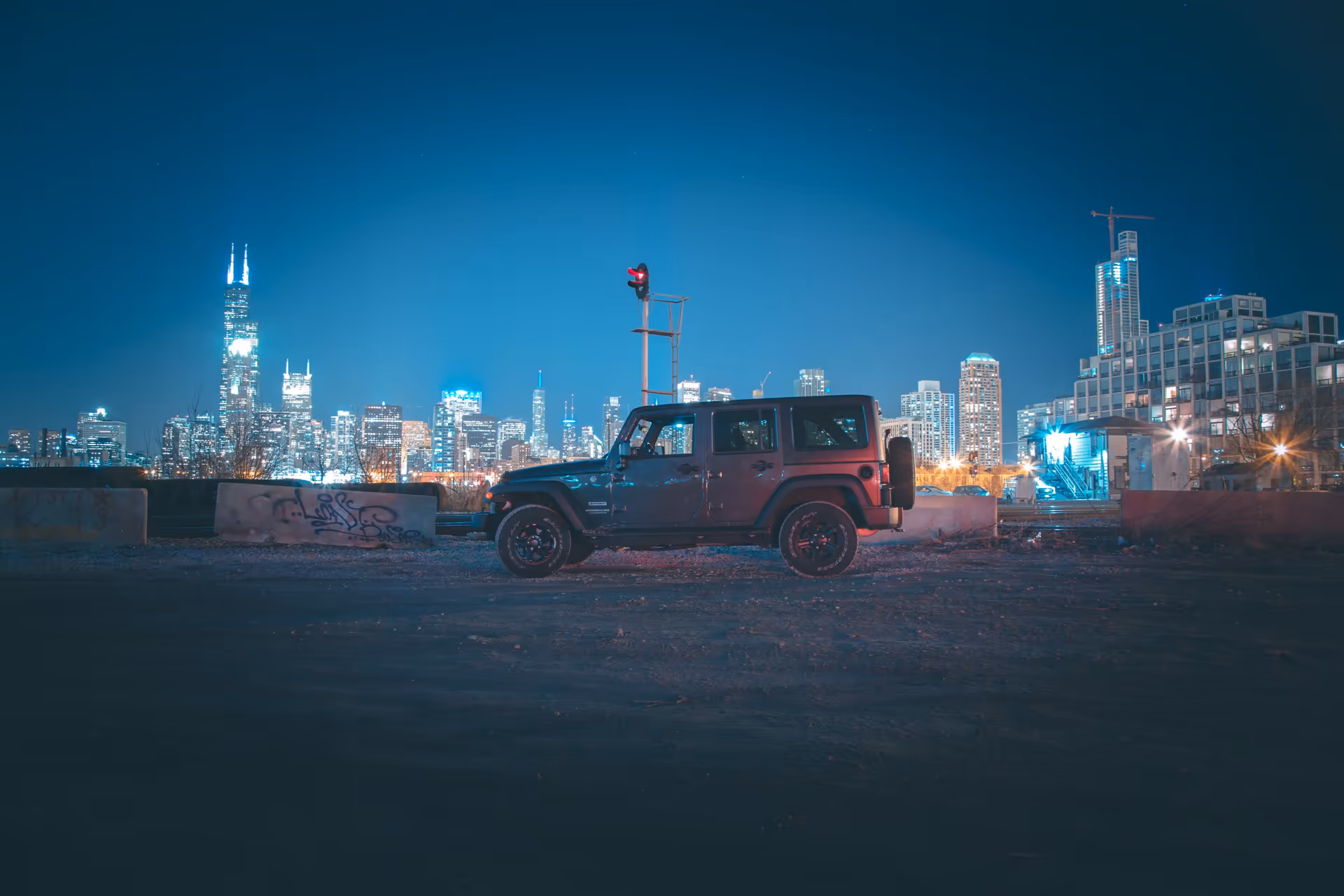 Un Jeep estacionado de noche en un lote de grava, con los rascacielos de Chicago al fondo