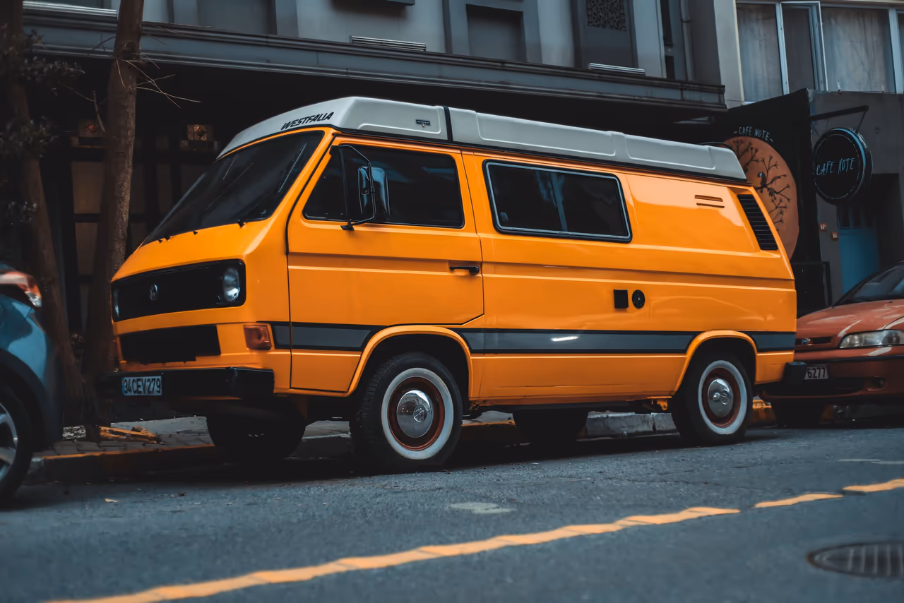 Una camioneta camper naranja estacionada en una calle de la ciudad