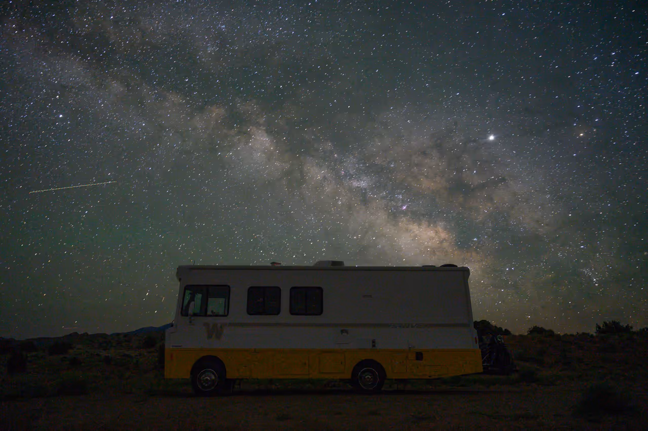 Una casa rodante vieja estacionada en el desierto bajo la Vía Láctea
